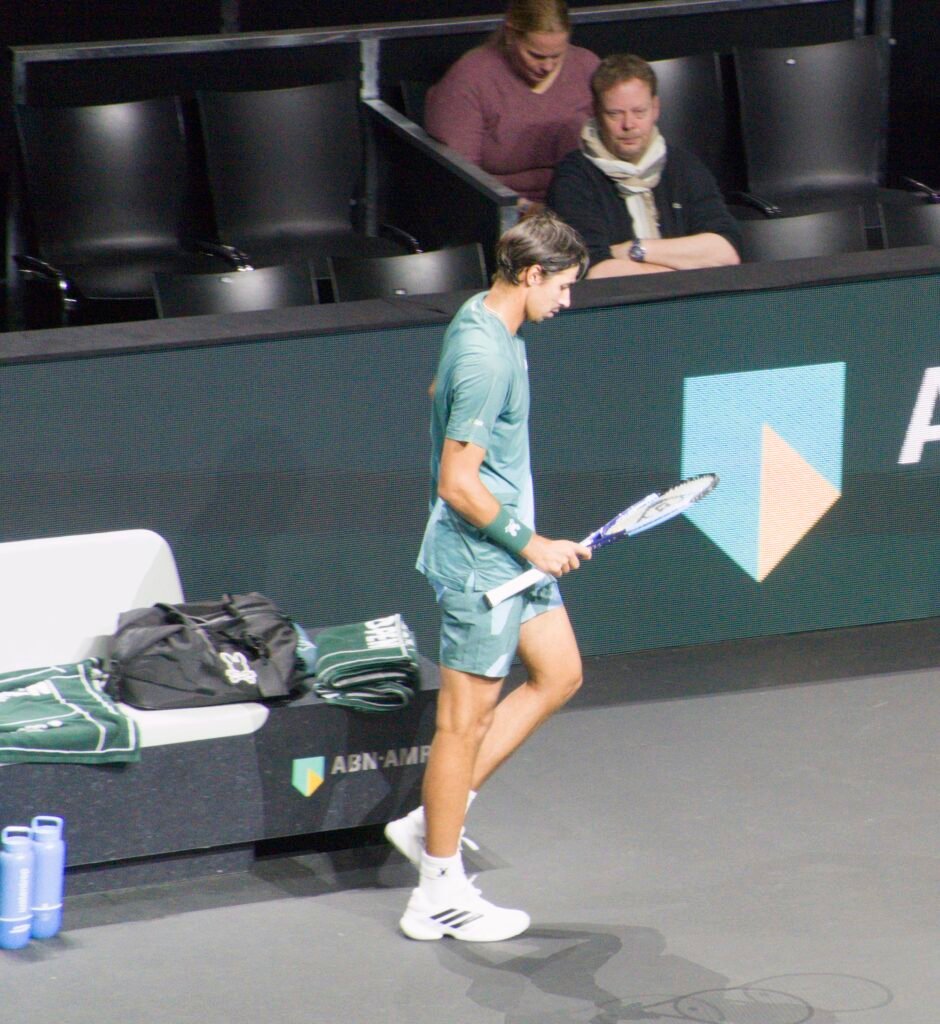 lexei Popyrin walks from his chair back onto court after the changeover during his match vs Félix Auger-Aliassime at Rotterdam 2026.