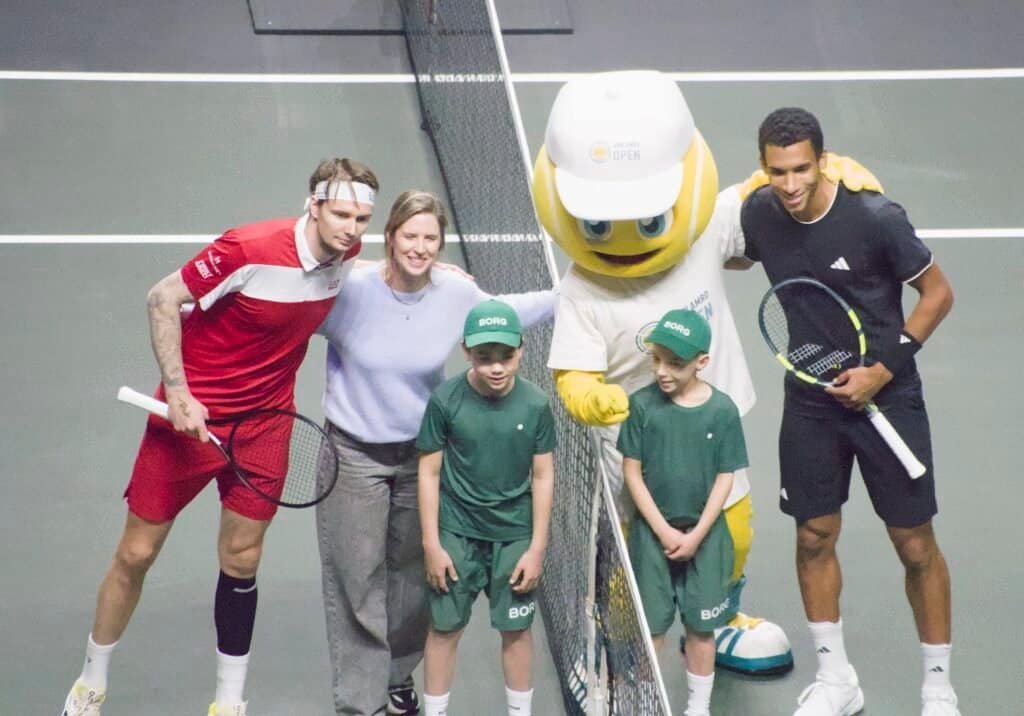 Felix Auger-Aliassime and Alexander Bublik pose at the net with the tournament mascot, two ball kids and an on-court guest before their Rotterdam 2026 semi-final.
