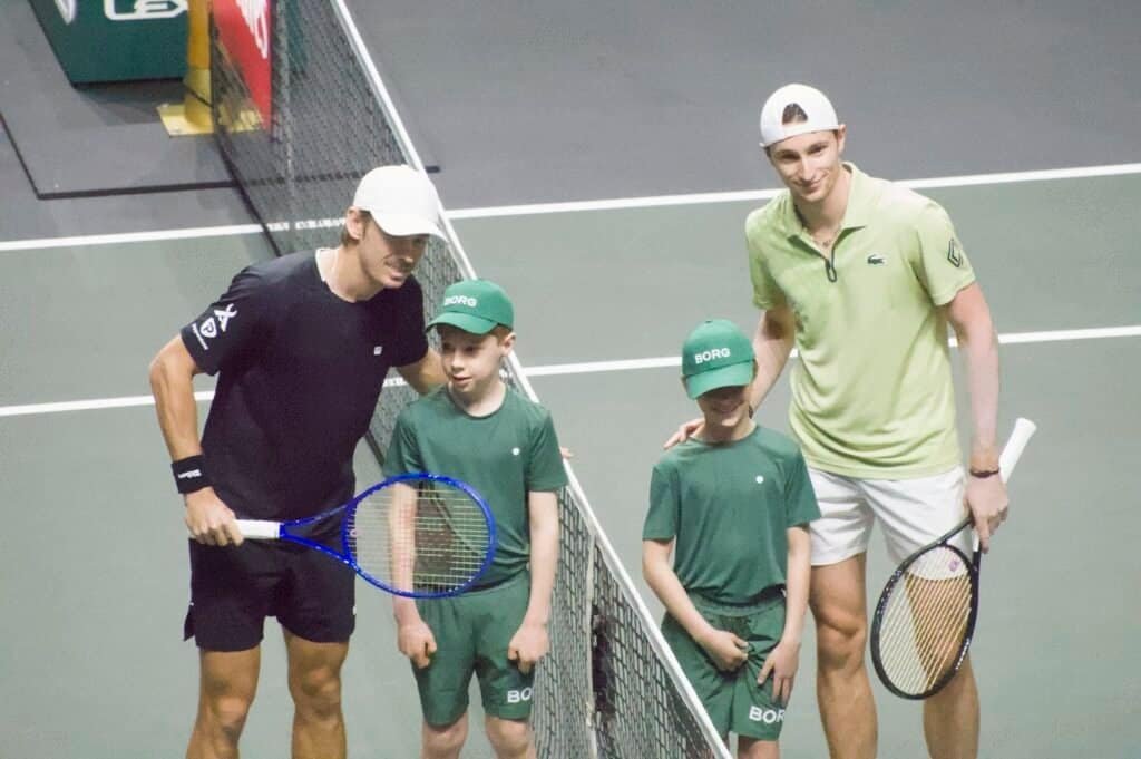 Alex de Minaur and Ugo Humbert pose at the net with the ABN AMRO Open mascot and two ball kids before their 2026 Rotterdam semi-final.
