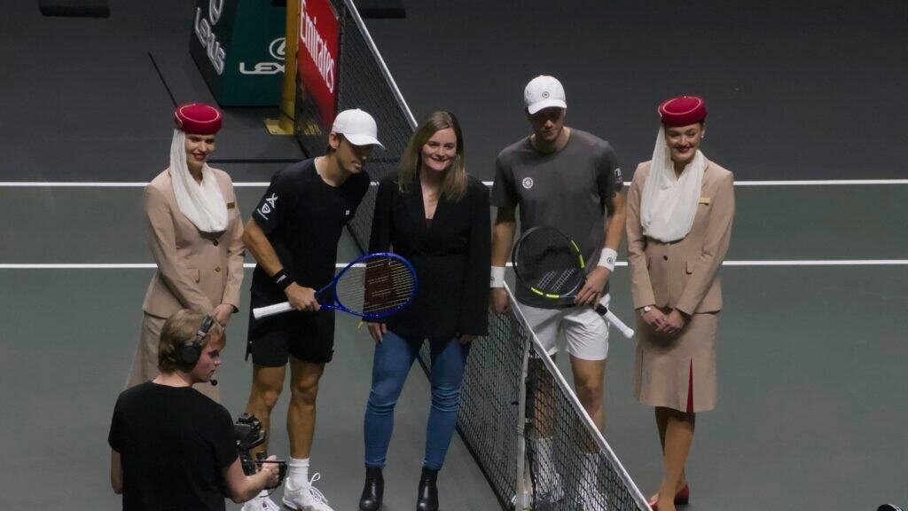 Alex de Minaur and Botic van de Zandschulp pose at the net with an on-court guest and Emirates crew before their quarter-final at the ABN AMRO Open Rotterdam 2026.