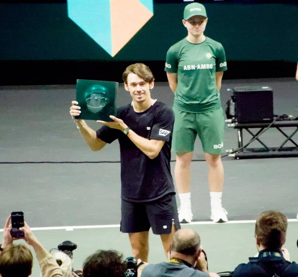 Rotterdam ATP 500 2026 champion receives trophy during on-court presentation ceremony with tournament staff.
