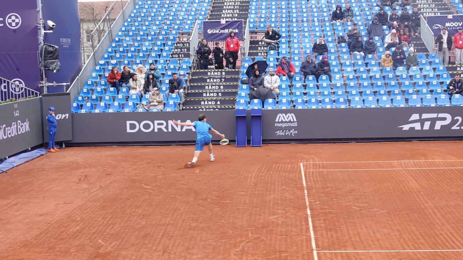 Le jeune joueur de tennis roumain Stefan Horia Haita frappe un revers sous le regard des spectateurs munis de parapluies au Tiriac Open