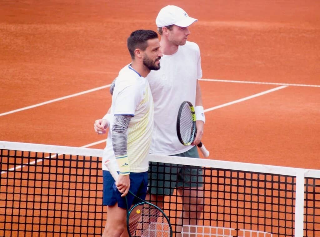 Los tenistas Damir Dzumhur y Botic van de Zandschulp posando en la red antes de su partido en Bucarest