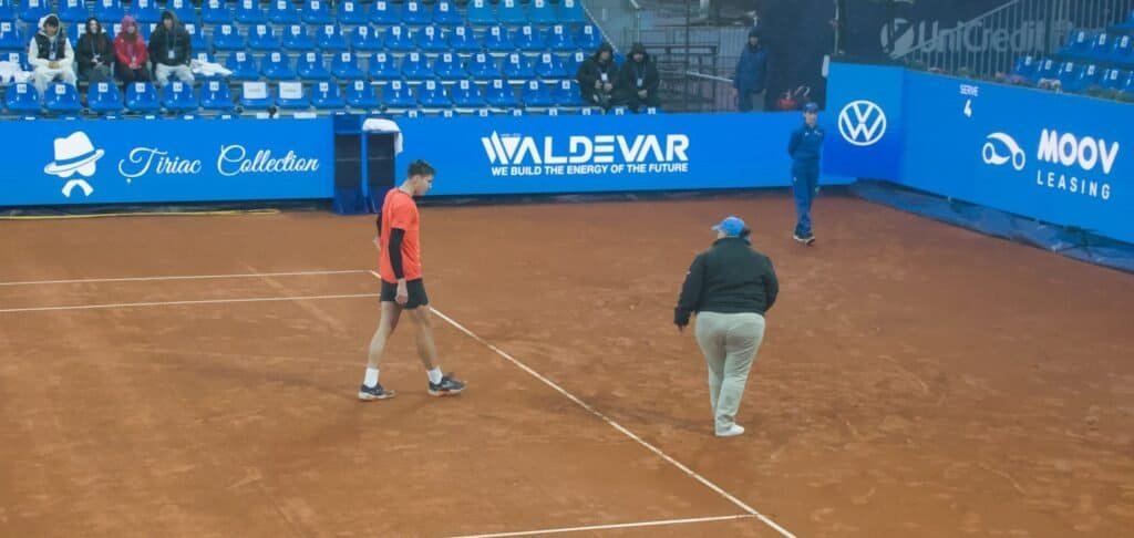 Tennis player Fabian Marozsan and the chair umpire inspecting the clay court surface during a rain delay