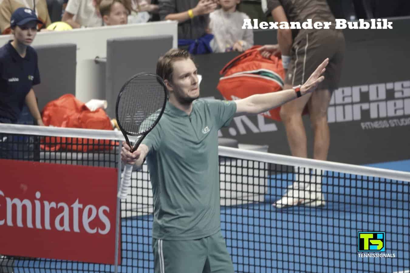 Alexander Bublik standing at the net with his racket in hand, acknowledging the crowd after a dramatic victory over Karen Khachanov at the ATP Almaty tournament.