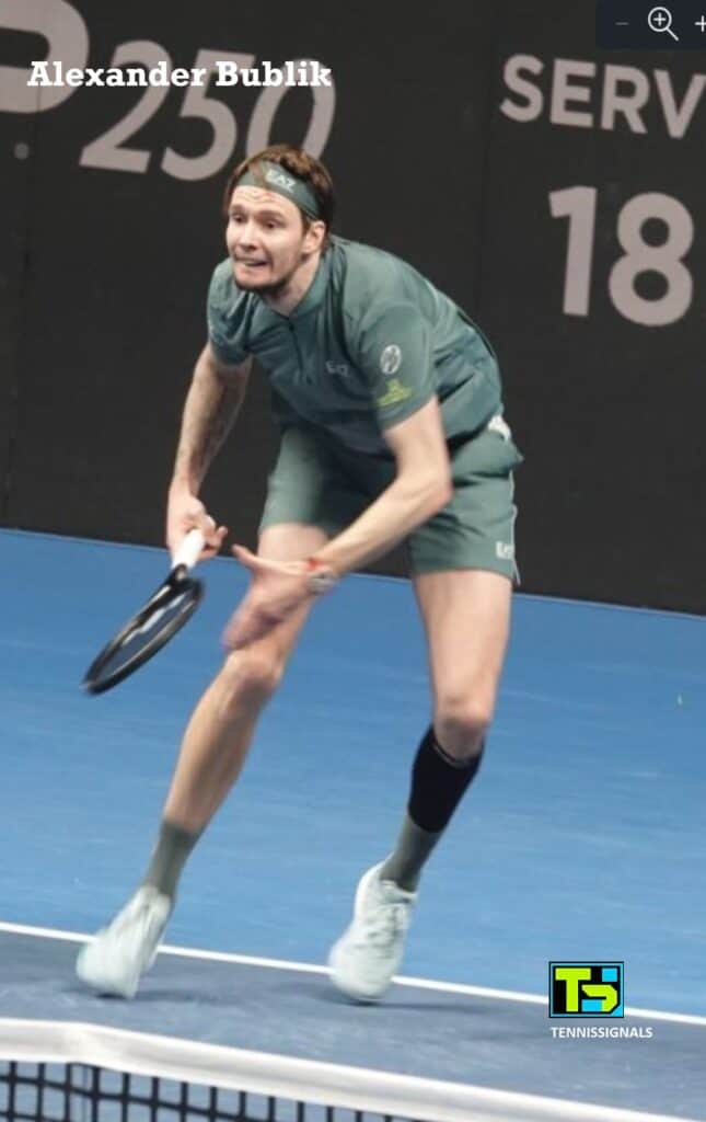 Alexander Bublik in a low tennis stance, fully focused and ready for a shot during his match against Karen Khachanov in Almaty.