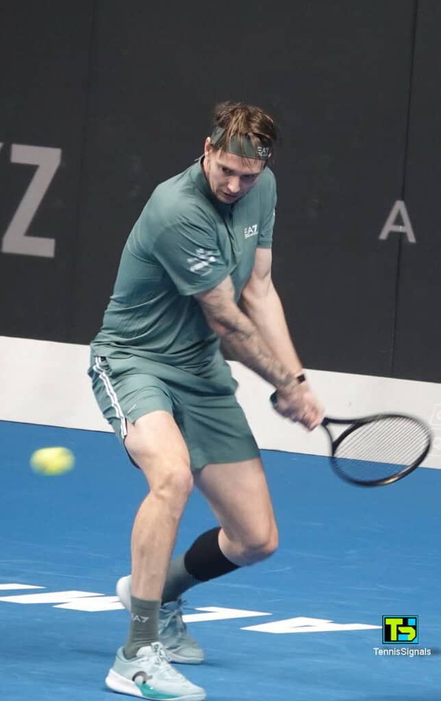 Alexander Bublik smiling and entertaining the crowd during an exhibition tennis match in Almaty.