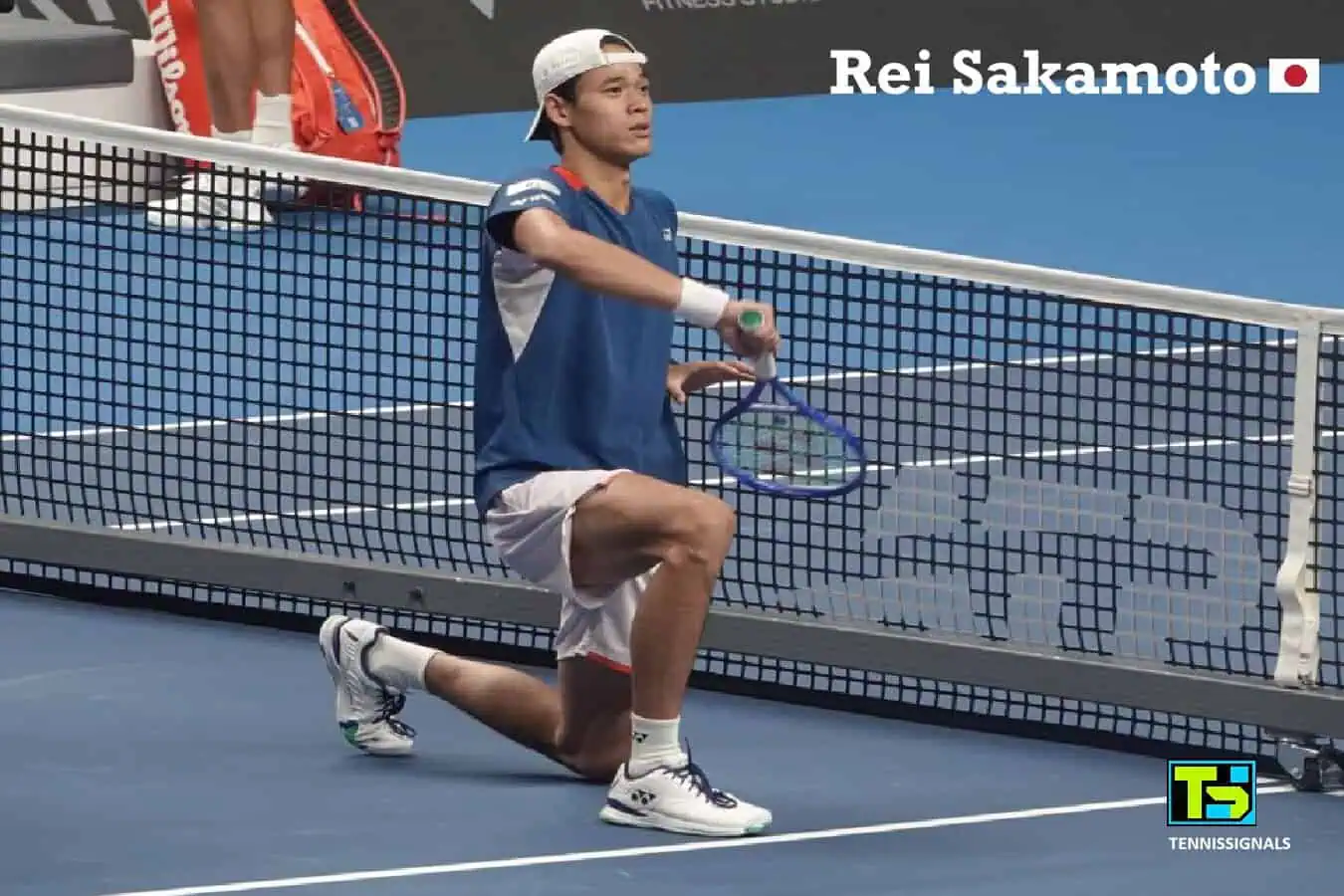 Japanese tennis player Rei Sakamoto kneeling on the court near the net and celebrating his victory by holding his racket like a samurai sword at the ATP Almaty Open.