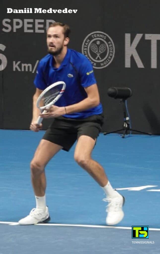 Daniil Medvedev con camiseta azul en posición de espera preparándose para golpear durante su partido contra Sho Shimabukuro en el torneo de Almaty.