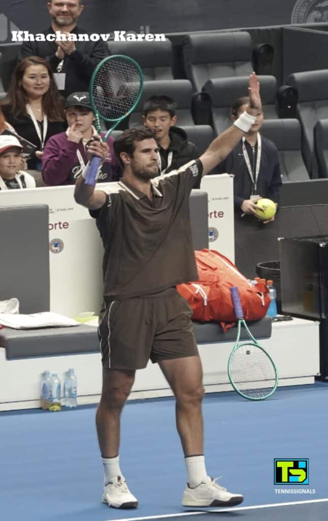 Karen Khachanov celebrando su victoria con los brazos en alto y la raqueta tras su partido contra Tomas Machac en el torneo de Almaty.