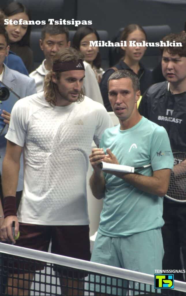 Stefanos Tsitsipas and Mikhail Kukushkin standing together at the net talking after Kukushkin's final career match at the Almaty tournament.